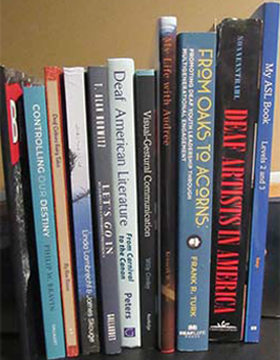 On a shelf stand twelve books by various Deaf authors.