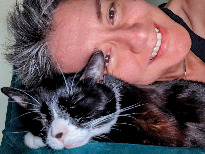 Close up of a smiling woman laying her head on a black and white whose eyes are closed.