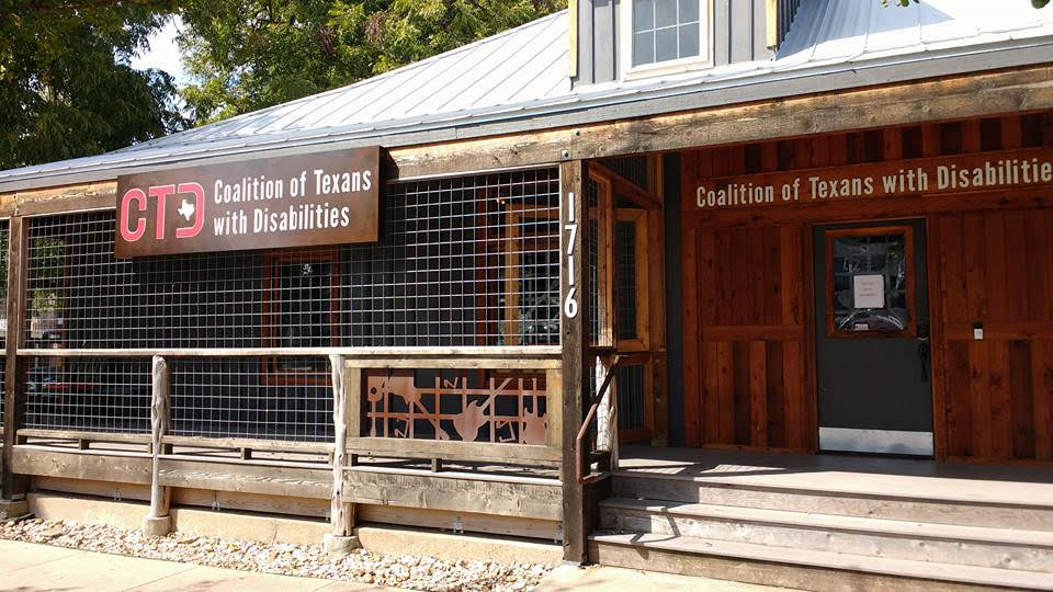 Wooden building with a long gated porch and metal roof. Signage displays the Coalition of Texans with Disabilities' name and logo.