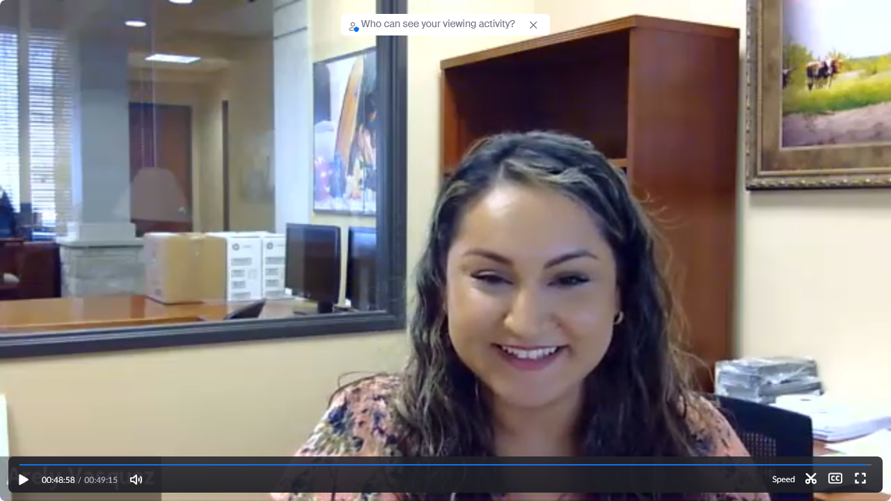 Screenshot of a smiling woman in an office setting, with playback controls at the bottom of the image.