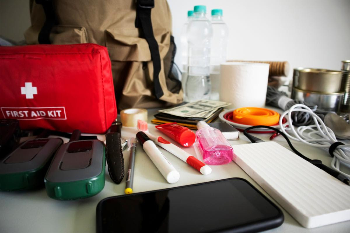 Photo of a first aid kit, battery packs, chargers, and other supplies laid out on a table